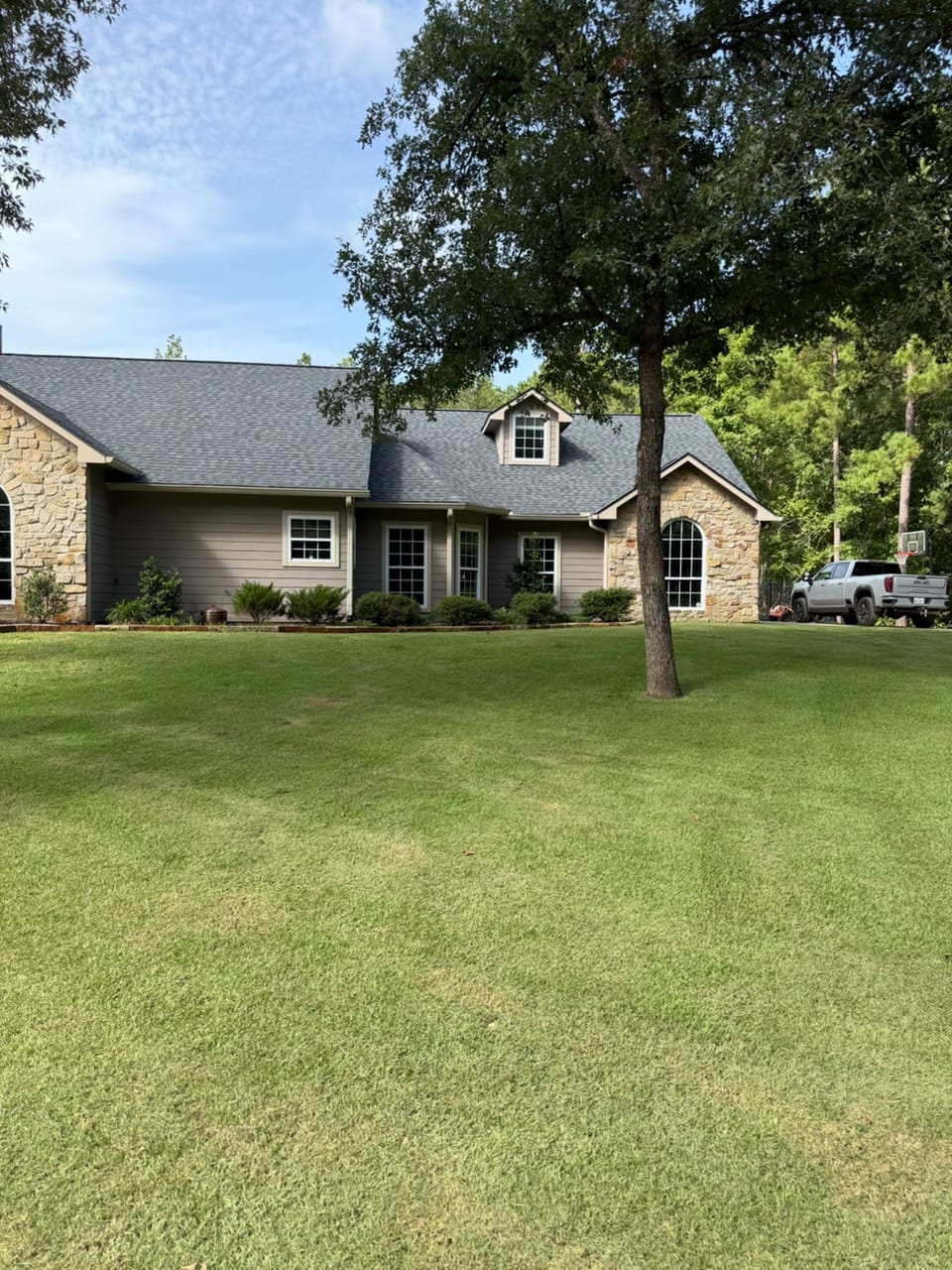 Manicured front lawn of a stone East Texas home after full-property service